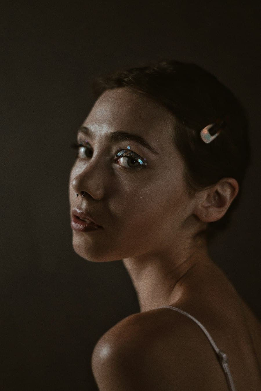 Close portrait lit low and warm, with iridescent colour brushed along the lash line